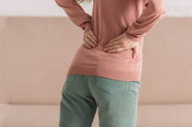 cropped view of woman holding hands on loin while suffering from back pain clipart