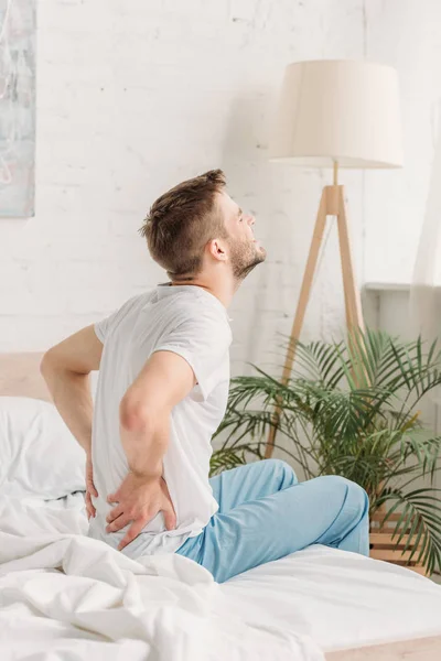 Young Man Sitting White Bedding Suffering Back Pain — Stock Photo, Image