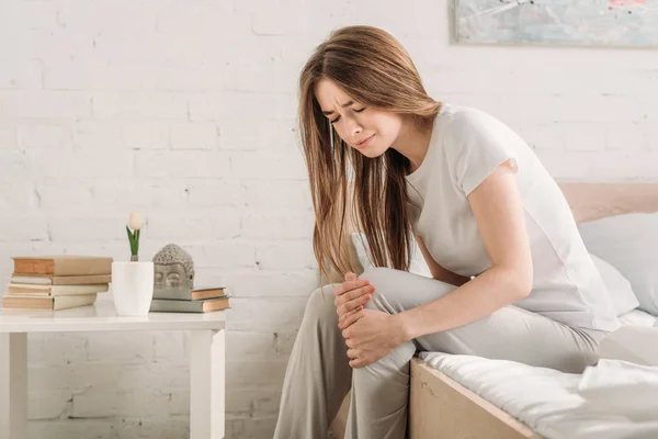 Frowned Girl Sitting Bed Bedside Table Suffering Knee Pain — Stock Photo, Image