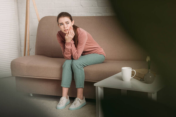 селективное внимание расстроенной девушки касаясь щеки при страдании от зубной боли
