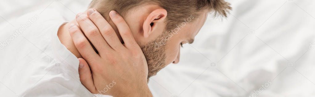 panoramic shot of young man suffering from neck pain