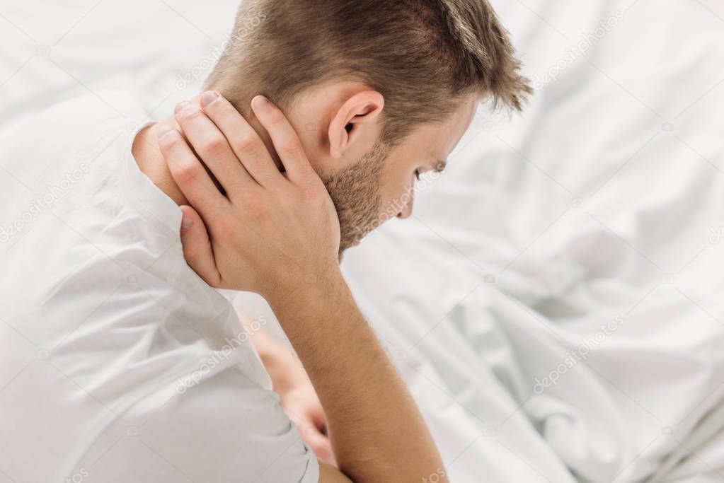 overhead view of young man suffering from neck pain