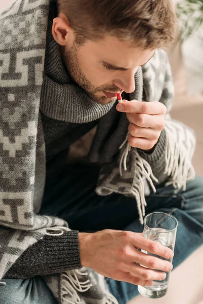 Hombre Enfermo Envuelto Manta Sosteniendo Vaso Agua Mientras Toma Medicamentos — Foto de Stock