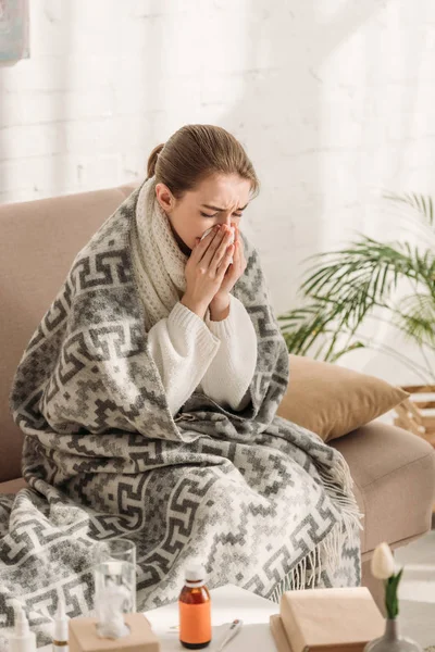 生病的女人 裹着毯子 坐在沙发上 用餐巾打喷嚏 — 图库照片