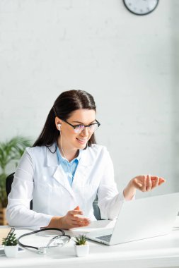 Güzel doktor, klinikteki laptopta hastayla çevrimiçi istişare yapıyor.