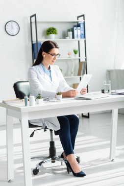 Güzel doktor, klinikte bilgisayarlı dijital tablet üzerinde online danışmanlık yapıyor.