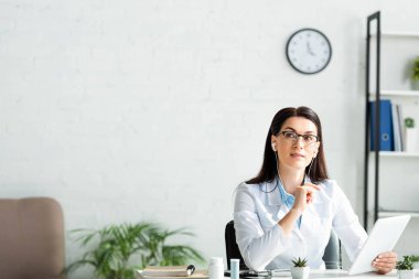 Ofisteki dijital tablette online danışmanlık yapan kulaklıklı çekici bir doktor.