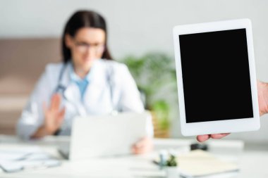 Klinikte elinde boş ekranla dijital tablet tutan bir adamın görüntüsü. Doktorun bilgisayarında online danışma yapması, seçici odaklanma. 