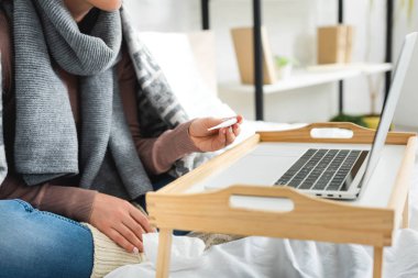 Ateşli bir kadının dizüstü bilgisayarında doktorla online istişare yaptığı görüntüler.