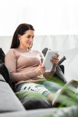 Kırık bacaklı gülümseyen kadın dijital tablet kullanan doktorla online görüşme yapıyor.