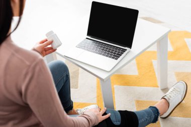 Kırık bacaklı, elinde haplar olan ve bilgisayarında doktorla internetten görüşen bir kadın. 