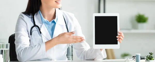 医生面带微笑的全景照片 在诊所办公室展示带有空白屏幕的数码平板电脑 — 图库照片