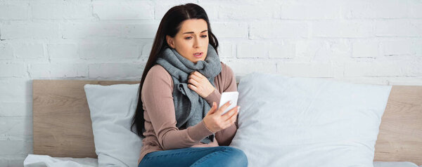 panoramic shot of attractive ill woman with flu having online consultation with doctor on smartphone