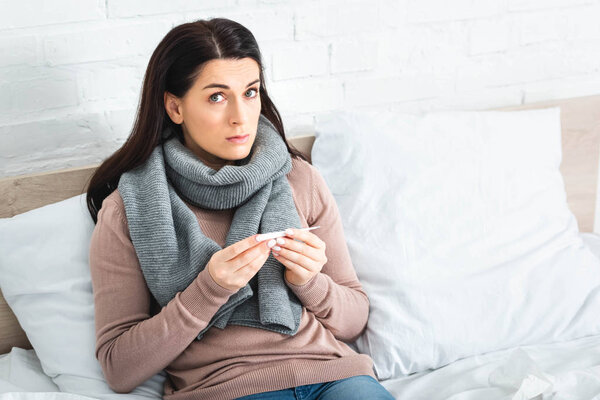 sick woman with thermometer having fever at home