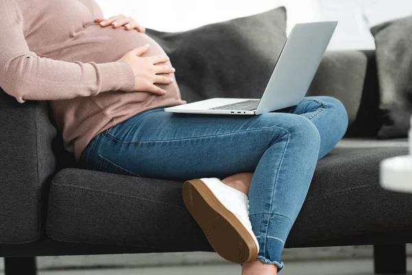お腹に触れた妊婦の様子を切り取り自宅のノートパソコンで医師とオンライン相談し — ストック写真