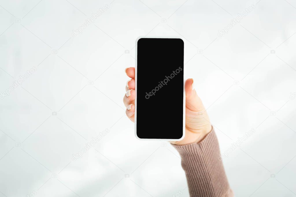 partial view of woman holding smartphone with blank screen