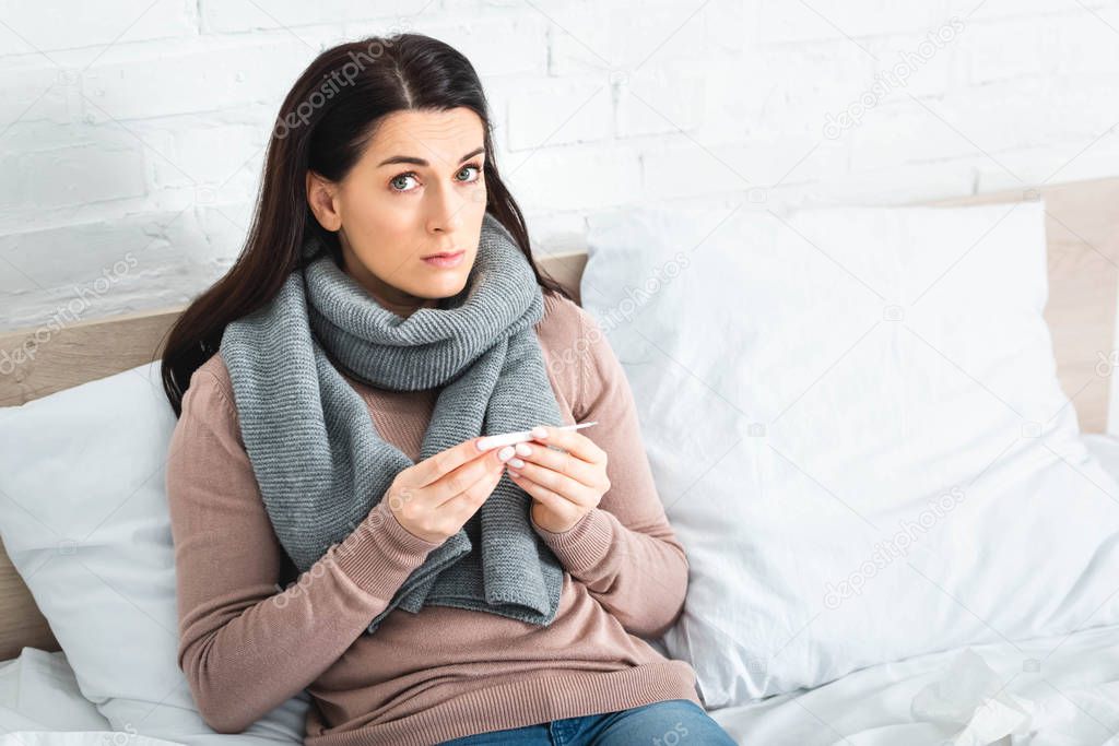 sick woman with thermometer having fever at home