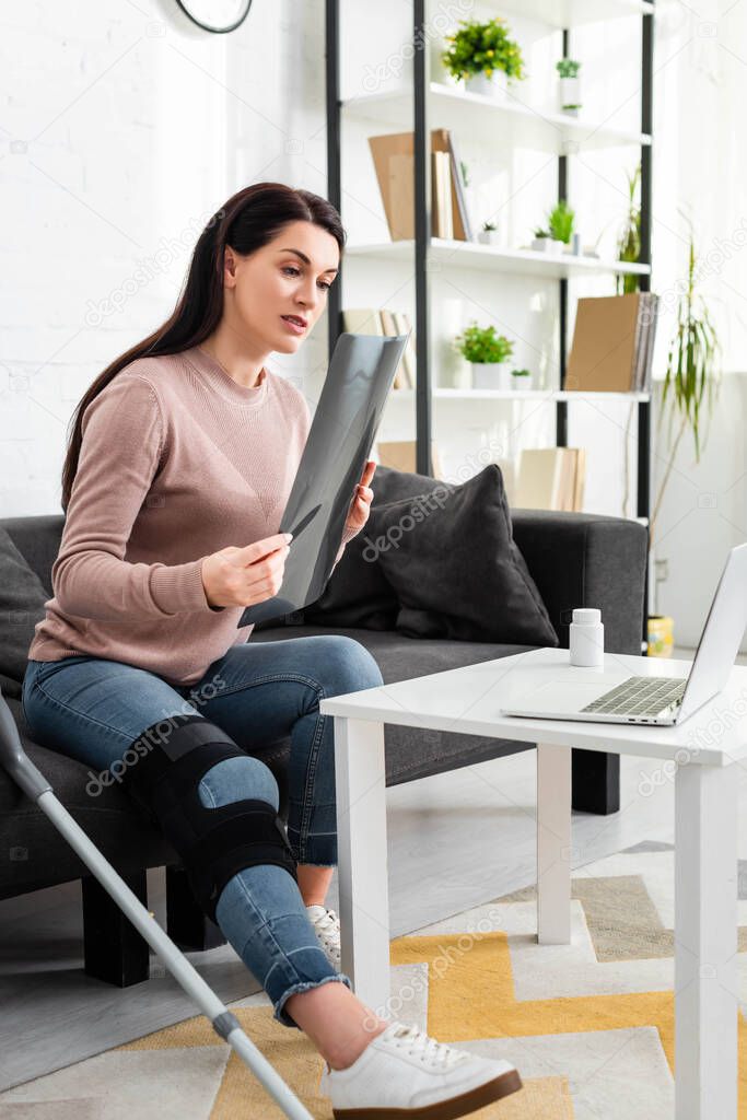 Woman showing x-ray of leg on online consultation with doctor on laptop