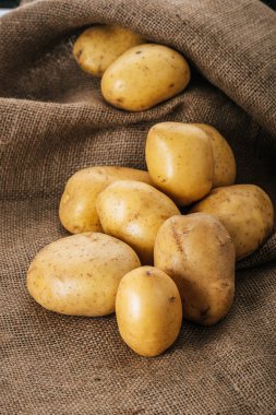 organic raw potatoes on brown rustic sackcloth clipart