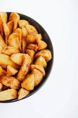 Beyaz tenceredeki lezzetli patates dilimlerinin üst görüntüsü.