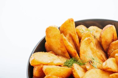 Lezzetli altın patates dilimlerinin, beyaz tenceredeki dereotun içine yakın görüntüsü.