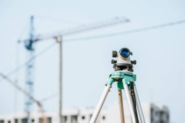 Digital level on tripod with construction site on background clipart