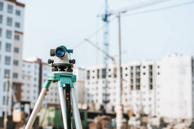 Arkaplanda inşaat alanı olan tripodda dijital seviye