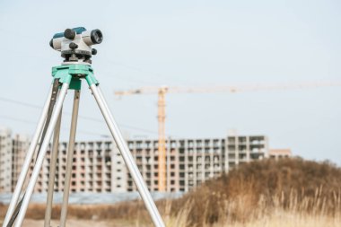 Arkaplanda inşaat alanı olan tripodda dijital seviye