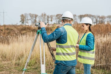 Surveyors working with digital level in field clipart