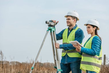 Surveyors with with digital level and tablet in field clipart