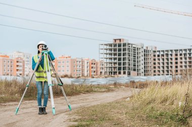 Surveyor measuring land with digital level on construction site clipart
