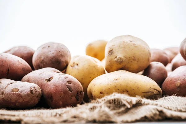 有機生ジャガイモの選択的焦点は白で隔離された茶色い素朴なサックスクロス — ストック写真