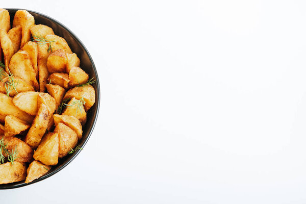 top view of delicious golden potato wedges with dill in bowl isolated on white