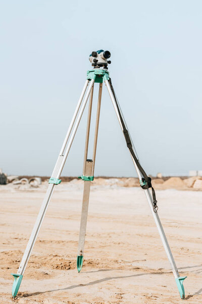 Цифровой уровень геодезических измерений на грунтовой дороге с голубым небом на заднем плане
