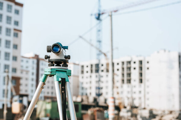 Digital level on tripod with construction site on background