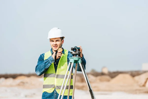 Usmívající Zeměměřič Klobouku Pomocí Digitální Úrovně Mluvení Rádiu — Stock fotografie