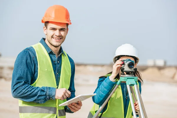 Sonriente Topógrafo Con Tableta Digital Colega Con Nivel Medición — Foto de Stock