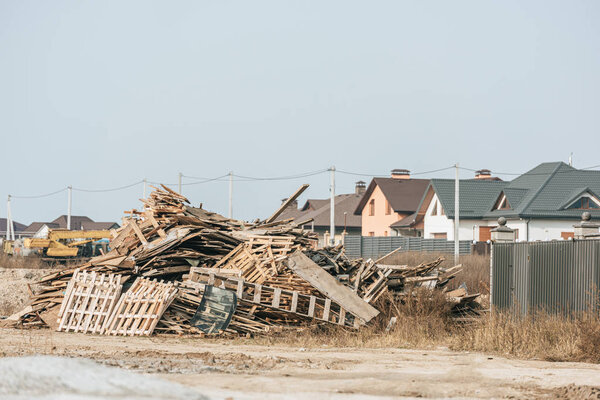 Stack of wooden pallets with houses at background