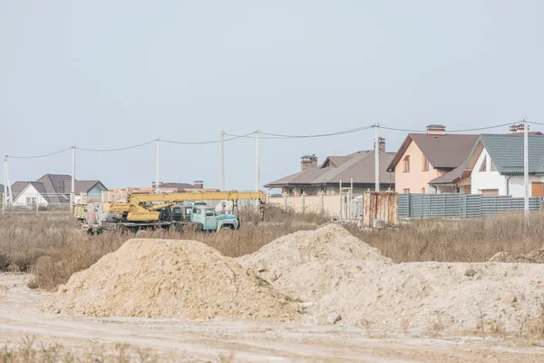 背景に建物クレーンや家と未舗装道路上の砂型 — ストック写真