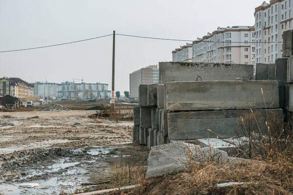Concrete blocks on dirt road and construction site at background