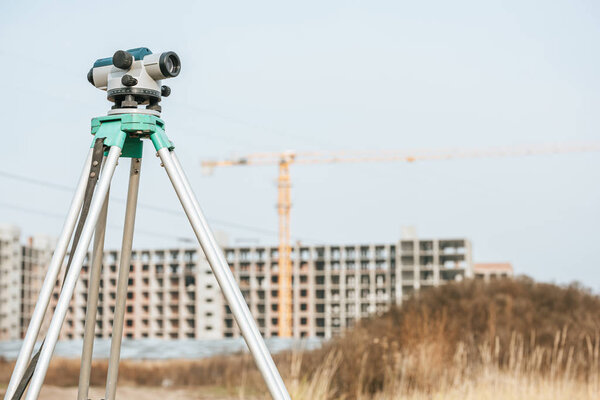 Digital level on tripod with construction site on background