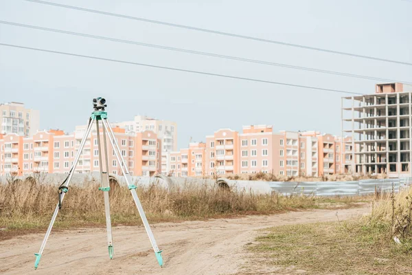 Digital level for geodesy measuring on dirt road with buildings at background