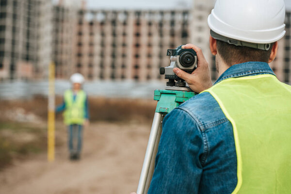 Selective focus of surveyors measuring land with digital level on construction site