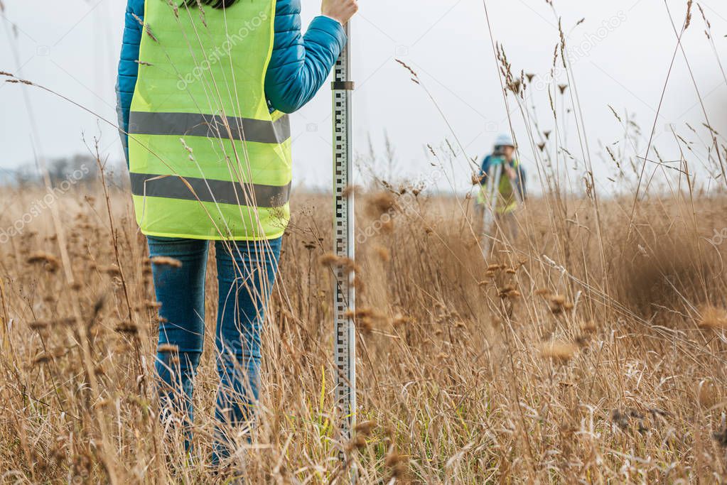 Cropped view of surveyors with survey ruler and digital level in field