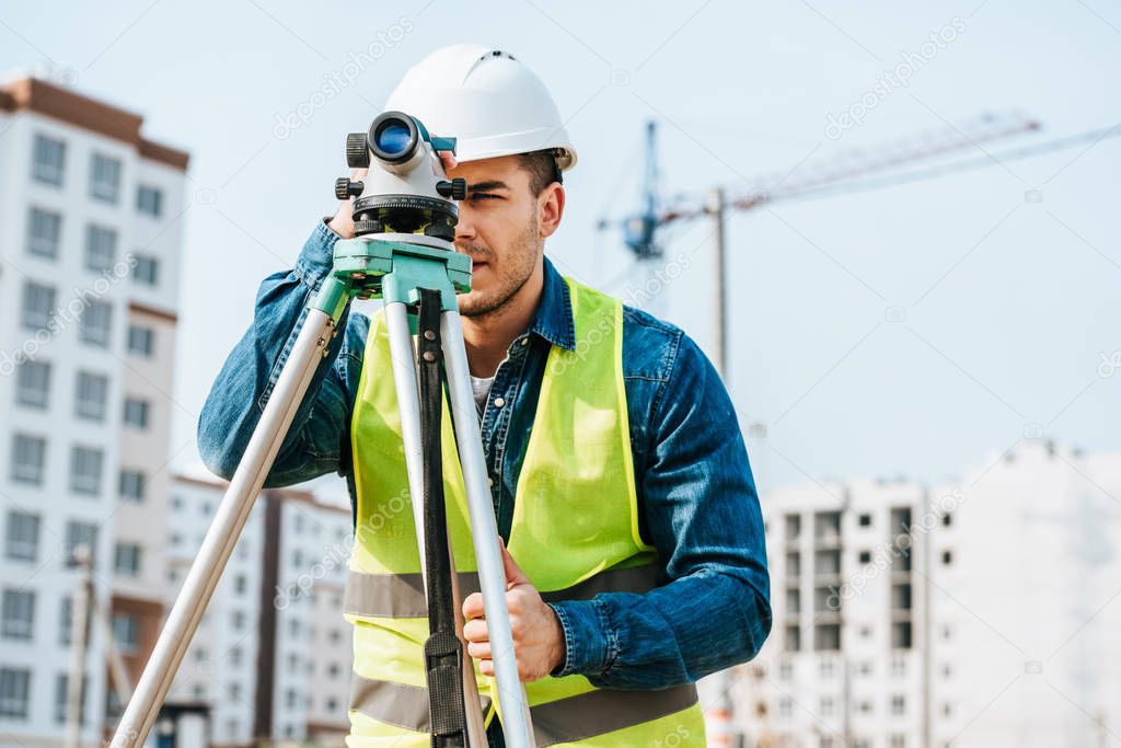 Surveyor looking throughout digital level on construction site 