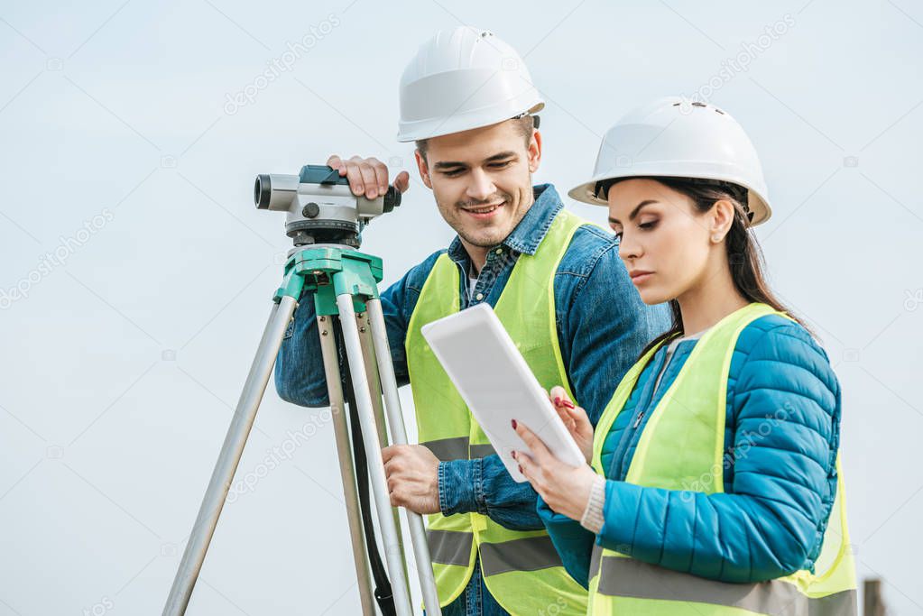 Surveyors with with digital level looking at tablet 