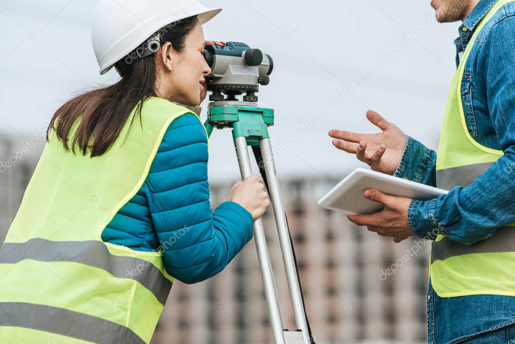 Cropped view of surveyors working with digital level and tablet