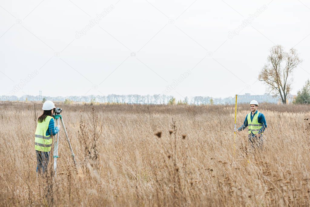 Surveyors measuring land with digital level and ruler in field