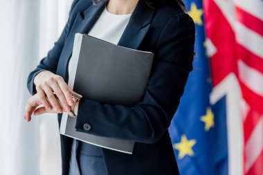 Diplomatın elinde klasör, bayrakların yanında durduğu görüntüler 