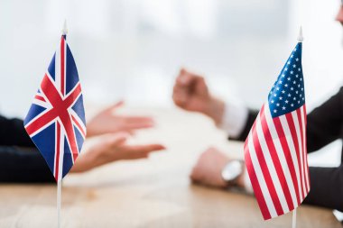 selective focus of flags of usa and united kingdom near diplomats  clipart